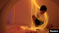 A boy relaxes with lights in a 'Snoezelen' room during yoga classes for children who typically have autism, brain injuries or developmental disabilities, in Lima, Peru, Jan. 27, 2012.