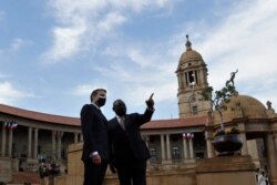 South African President Cyril Ramaphosa, right, and his French counterpart Emmanuel Macron talk during a welcoming ceremony at the government's Union Buildings, in Pretoria, May 28, 2021.