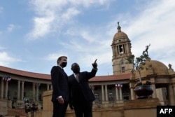 South African President Cyril Ramaphosa, right, and his French counterpart Emmanuel Macron talk during a welcoming ceremony at the government's Union Buildings, in Pretoria, May 28, 2021.
