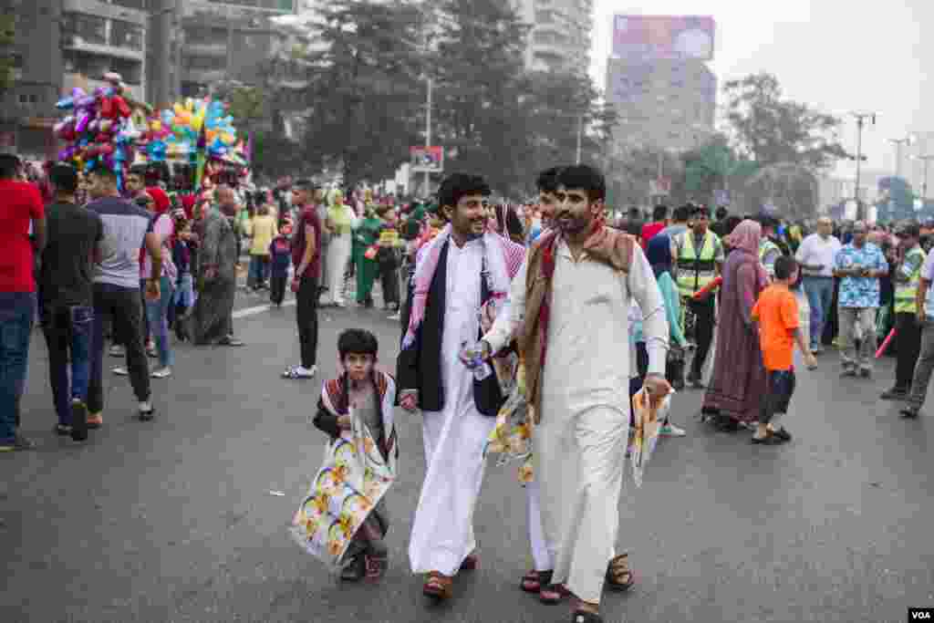 Tiga pria berpakaian tradisional Yaman tengah berjalan menuju lokasi sholat Idul Fitri di lapangan Mostafa Mahmoud di Kairo, Mesir, 25 Juni 2017. (H. Elrasam/VOA)