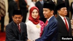 President Joko Widodo (kanan) berjabat tangan dengan Menteri Sosial baru, Idrus Marham (kiri), didampingi istri, Ridho Ekasari (tengah), seusai pelantikan di Istana Presiden, Jakarta, 17 Januari 2018. 