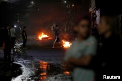 People are seen next to barricades along a street at a protest during curfew while the country is still mired in chaos over a contested presidential election in Tegucigalpa, Honduras, Dec. 3, 2017.