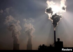 FILE- A coal-burning power plant behind a factory in China's Inner Mongolia Autonomous Region, Oct. 31, 2010.