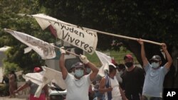 Salvadoreños agitan carteles solicitando alimentos en la carretera Golden en Ilopango, El Salvador, el 19 de mayo de 2020.