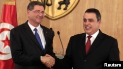 Tunisia's Prime Minister Habib Essid, left, leading a government that combines secular and Islamist parties, shakes hands with his predecessor, Mehdi Jomaa, during a handover ceremony in Tunis, Feb. 6, 2015. 