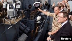 FILE: German Defense Minister Jung, right, and Captain Kay-Achim Schoenbach, second from right, wave as the German navy frigate Karlsruhe sails out of the harbor in Djibouti. 