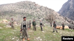 PKK fighters stand guard during the release of eight Turkish prisoners in the northern Iraqi city of Dohuk, March 13, 2013. (Reuters)