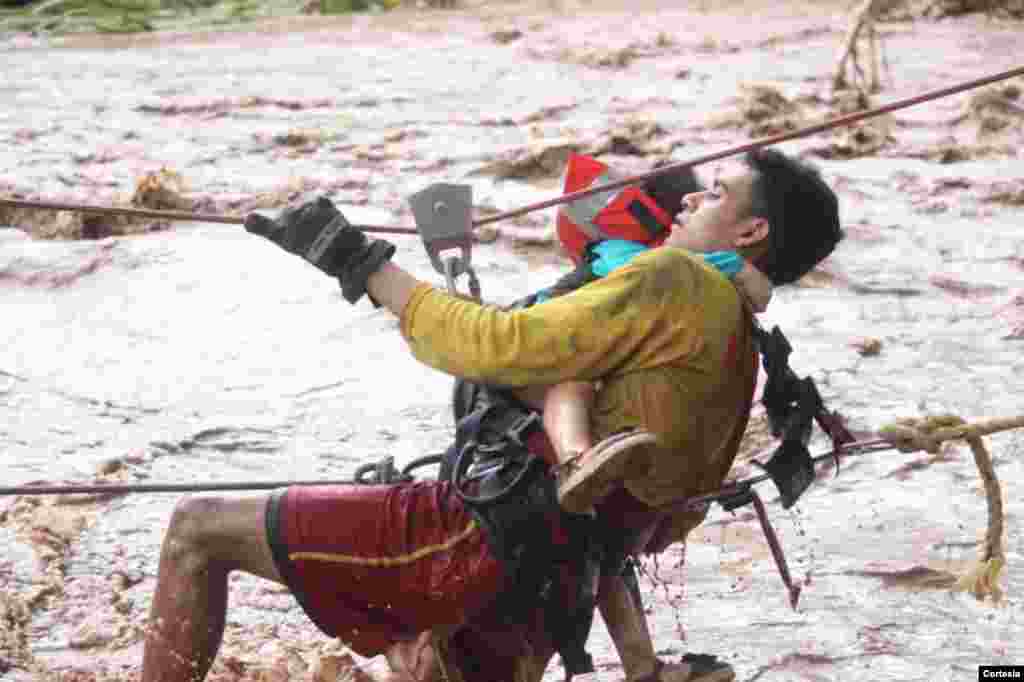 Un bombero hondure&#241;o rescata a una ni&#241;a en Junquillo, Honduras, durante el desbordamiento del r&#237;o Cececapa. Foto: Cortes&#237;a presidencia Honduras.