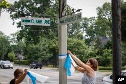 FILE - Denise Koesterman, right, and Alison Lebrun, left, tie blue-and-white awareness ribbons along Springfield Pike near the family home of Otto Warmbier, a 22-year-old University of Virginia undergraduate student who was imprisoned in North Korea.