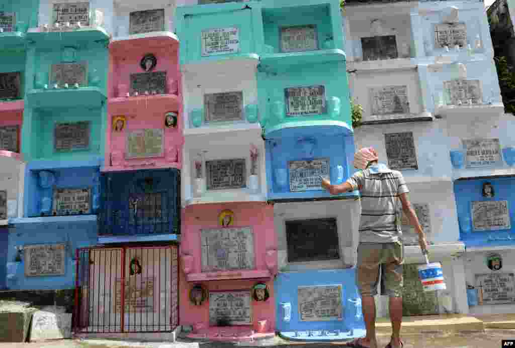 A worker paints one of the tombs at a cemetery in Manila ahead of the traditional All Souls&#39; day on November 1. Millions across the Philippines will visit cemeteries to pay their respects to their dead. 