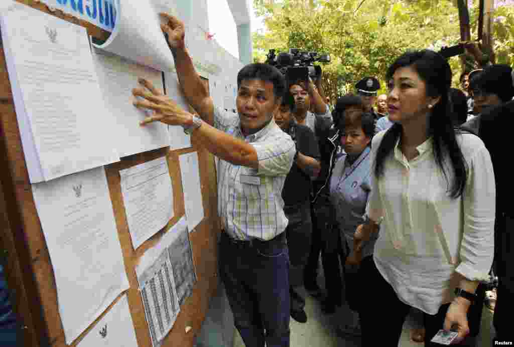Thai Prime Minister Yingluck Shinawatra, right, checks a list of voters' names before voting at a polling station in Bangkok, March 30, 2014.