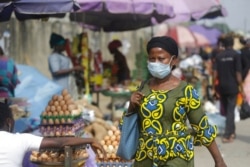 FILE - A woman wearing a face mask to protect against the novel coronavirus walks on a street in Lagos, Nigeria, Dec. 31, 2020.
