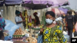 FILE - A woman wearing a face mask to protect against the novel coronavirus walks on a street in Lagos, Nigeria , Dec. 31, 2020. 