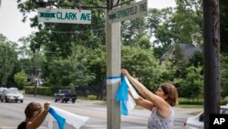 FILE - Denise Koesterman, à droite, et Alison Lebrun, à gauche, accroche des rubans bleus près de la maison d'Otto Warmbier, a 22-year-old University of Virginia undergraduate student who was imprisoned in North Korea.