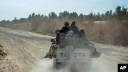 FILE - Afghan refugees sit in the back of a truck to go to Iran through the desert after crossing the borders of Afghanistan and Pakistan, on the outskirts of Zaranj city, Afghanistan, Dec. 24, 2023. 