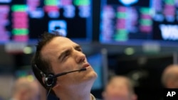 Stock trader Gregory Rowe works at the New York Stock Exchange, Wednesday, March 18, 2020 in New York. Global stock markets have sunk in a third day of wild price swings after President Donald Trump promised to prop up the U.S. economy through the…