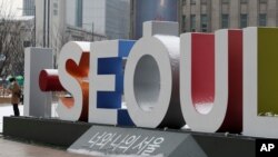 Un hombre con mascarilla cerca del logo de Seúl, la capital de Corea del Sur, en el centro de la ciudad, el domingo 13 de diciembre de 2020.