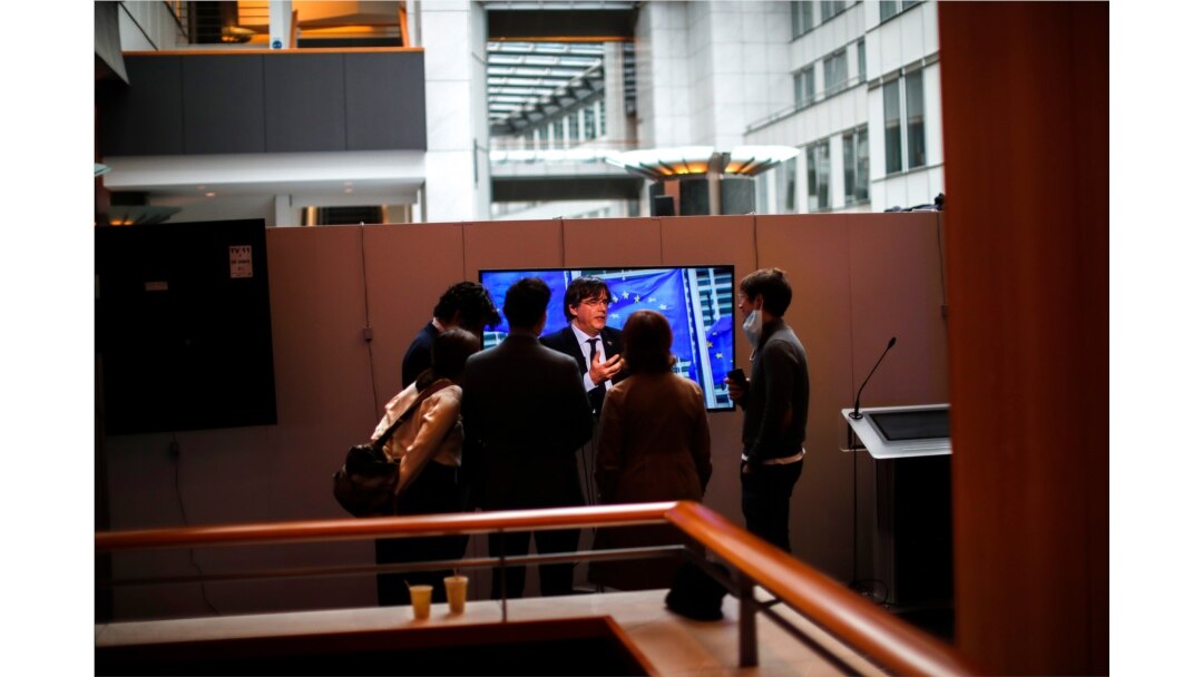 Warga berkumpul di sekitar televisi yang menayangkan wawancara dengan Anggota Parlemen Eropa, Carles Puigdemont di Parlemen Eropa di Brussel, Selasa, 9 Maret 2021.