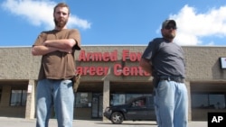 Allen Bowles, left, and Clint Janney, members of the 3 Percent Irregulars Militia, stand guard outside a military recruiting center in Columbus, Ohio, July 21, 2015.