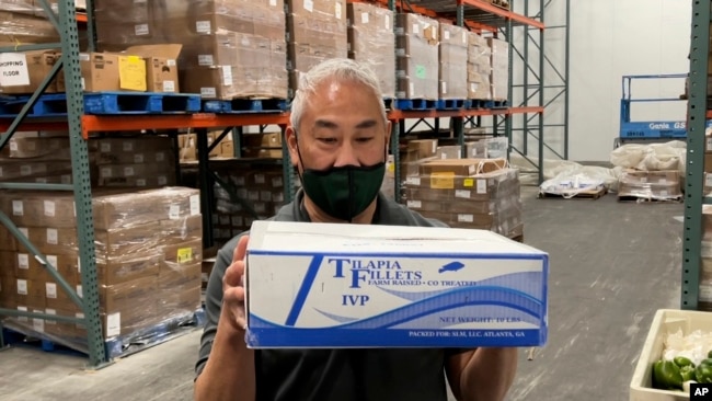 Wilken Louie, direktur sumber daya di Alameda County Community Food Bank, memegang sekotak filet ikan nila beku, yang harganya menjadi lebih mahal tahun ini, di Oakland, California, 5 November 2021.