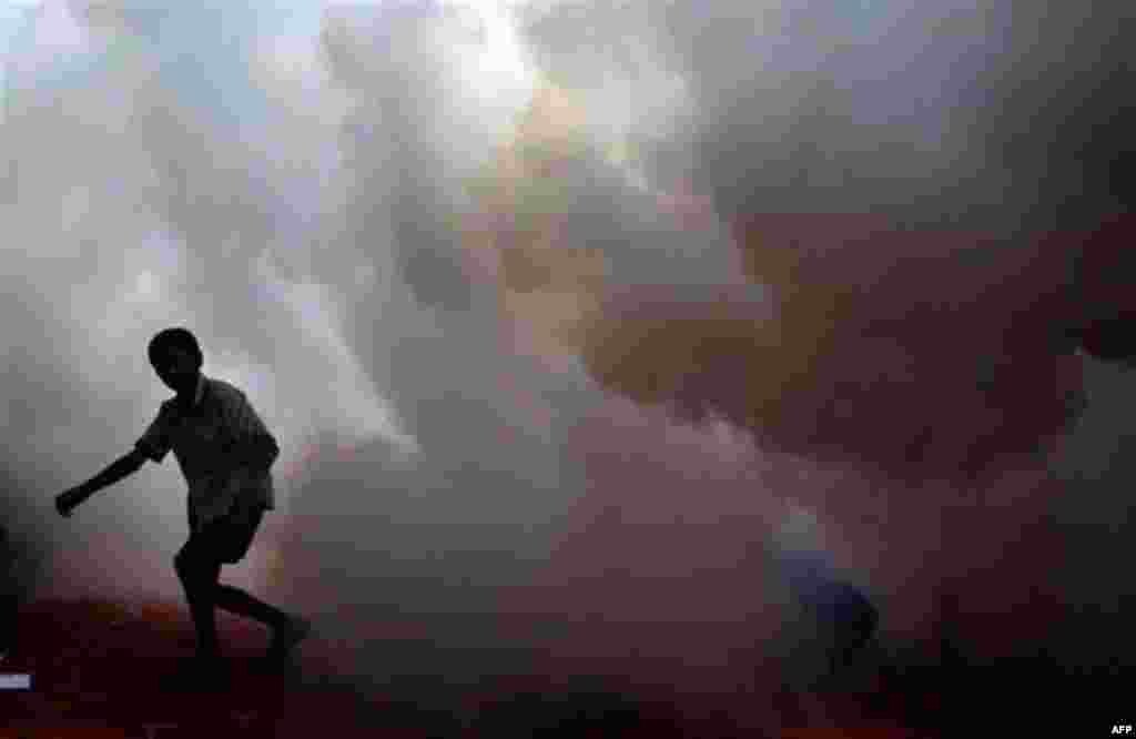 An Indian boy is seen in the foggy streets as health workers fumigate the vicinity with anti-mosquito spray, in Mumbai, India, Tuesday, Oct. 12, 2010. The Indian government has launched an all out effort to wipe out the female Aedes mosquitoes that transm