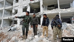 28일 시리아 북부 코바니 지역에서 쿠르드족 병사들이 폐허가 된 건물 잔해 위에 서 있다.