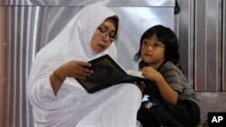 An Indonesian woman reads a copy of the Koran next to a young boy on the first day of the holy Islamic month of Ramadan in Jakarta, 11 Aug 2010