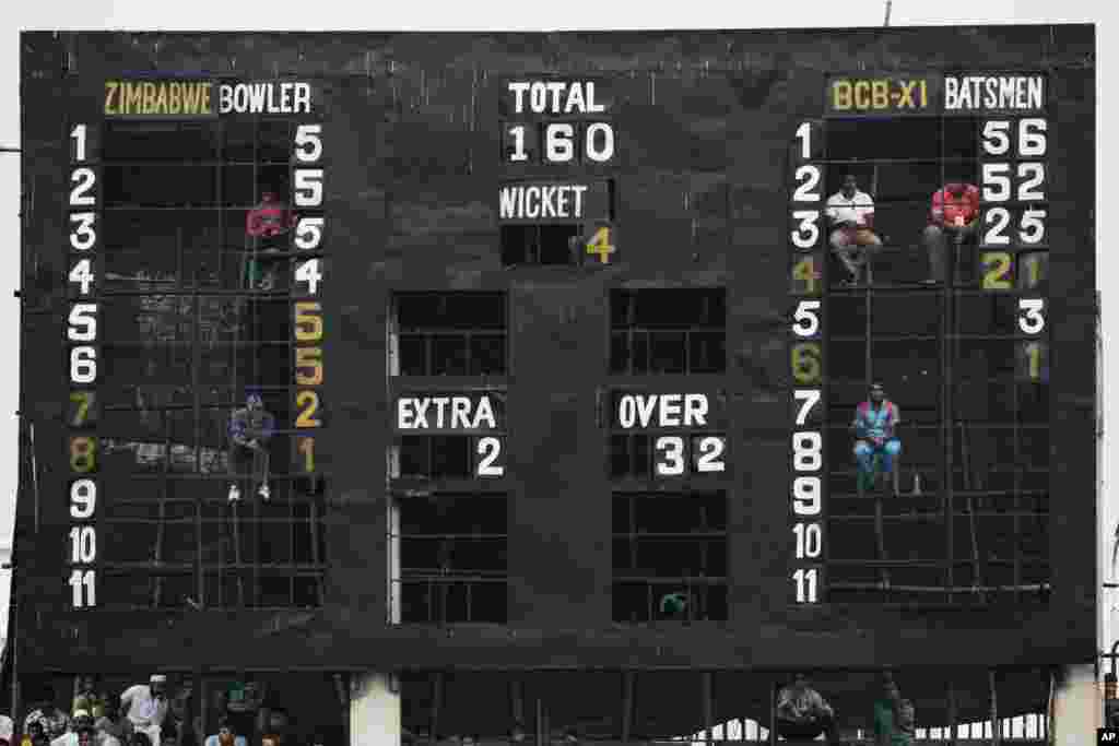 Men sit inside a giant scoreboard to change scores during a warm up match between Zimbabwe and Bangladesh Cricket Board XI in Fatullah, Bangladesh.