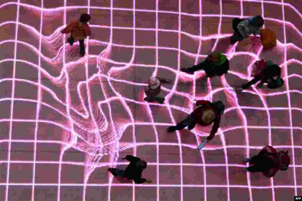 People walk over the interactive installation "Onskebronn", Norwegian for wishing well, at A central station in Berlin, Germany, Thursday, Oct. 14, 2010. The moving paths of visitors are followed on that LED-platform and retraced as reprocessed projection