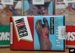 FILE - Warning signs are printed on packs of cigarettes for sale in Bangkok, Thailand.