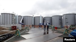2020年1月15日，工人站在福岛第一核电站核废水储存设备旁。
