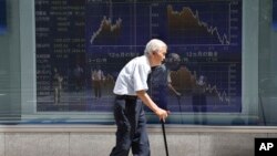 FILE - An elderly man walks by an electronic stock board of a securities firm in Tokyo, Aug. 19, 2016. Elderly healthcare poses significant fiscal challenges all across Asia, experts say.