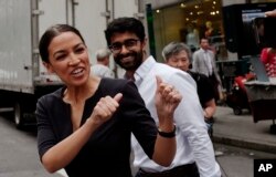 FILE - Alexandria Ocasio-Cortez, the winner of a Democratic congressional primary in New York, greets a passerby in New York, June 27, 2018, the morning after she upset U.S. Rep. Joe Crowley in a primary election.