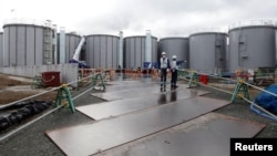 FILE - Workers are seen near storage tanks for radioactive water at Tokyo Electric Power Co's (TEPCO) tsunami-crippled Fukushima Daiichi nuclear power plant in Okuma town, Fukushima prefecture, Japan. January 15, 2020. (REUTERS/Aaron Sheldrick)