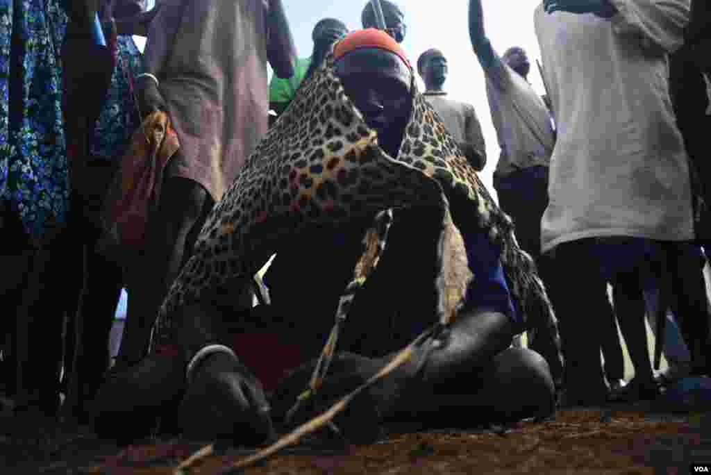 A Bor Dinka wrestler sits on the ground draped in a leopard skin before the "Wrestling for Peace" tournament at Juba Stadium in South Sudan's capital, April 16, 2016. (J. Patinkin/VOA)