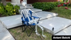 Una figura de un esqueleto sentado en una silla frente a una casa como parte de la decoración de Halloween en un barrio de Miami, Florida. (Foto: Antoni Belchi / VOA)