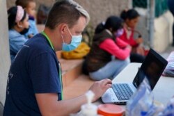 FILE - Volunteer Mark McDonald enters data at a clinic set up for asylum-seekers waiting in Matamoros, Mexico, Nov. 19, 2020.