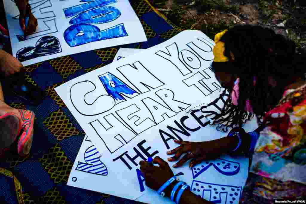 Une manifestante finalise une pancarte lors du rassemblement "Africans 4 BLM" à Washington DC, le 14 juin 2020. (VOA/Nastasia Peteuil)