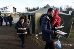 Migrants receive food at the transport and logistics center near the Bruzgi border point on the Belarusian-Polish border in the Grodno region, Nov.20, 2021.