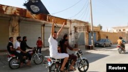 A resident of Tabqa city touring the streets on a motorcycle waves an Islamist flag in celebration after Islamic State militants took over Tabqa air base, in nearby Raqqa city, Aug. 24, 2014.