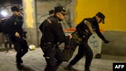 Des policiers espagnols transportent un homme lors d'une manifestation à la suite du décès d'un vendeur ambulant dans le quartier de Lavapies à Madrid, le 15 mars 2018.