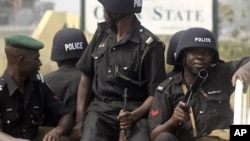 Police watch as people protest after the government suddenly removing subsidies on gasoline prices in Abeokuta, Nigeria, January 5, 2012.