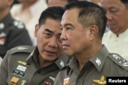 FILE - The next Thai national police chief Chakthip Chaijinda (L) talks with Thai national police chief Somyot Poompanmuang (R) during a religious ceremony near the Erawan shrine in central Bangkok, August 21, 2015.