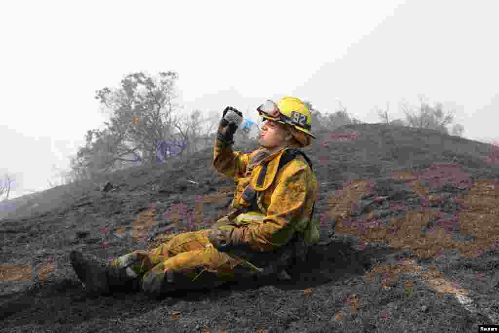 Seorang anggota pemadam kebakaran beristirahat saat berupaya memadamkan kebakaran hutan di Mandeville Canyon, Los Angeles, California.