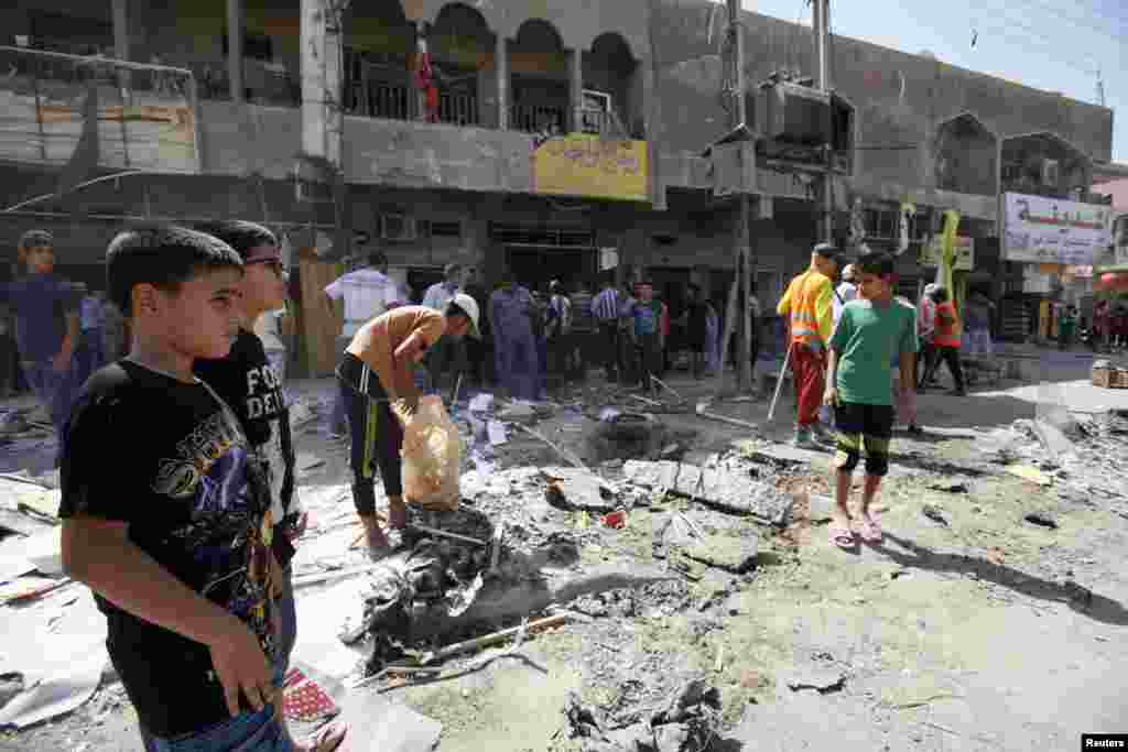 Youths look at the site of a car bomb attack in Baghdad's al-Shaab district, August 28, 2013.