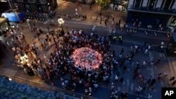 People gather at a memorial tribute of flowers, messages and candles to the victims on Barcelona's historic Las Ramblas promenade on the Joan Miro mosaic, embedded in the pavement where the van stopped after killing at least 14 people in Barcelona, Spain, Aug. 18, 2017.