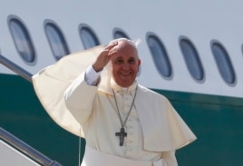 Pope Francis waves as he boards his plane to leave for his pastoral visit to South Korea, at the Fiumicino airport in Rome, Aug. 13, 2014.
