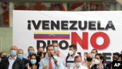Flanqueado por compañeros, el líder de la oposición venezolana Juan Guaidó habla durante una conferencia de prensa, un día después de las elecciones parlamentarias, en Caracas, el 7 de diciembre de 2020.