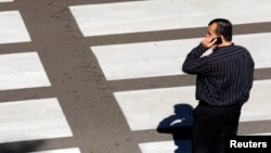 A man talks on his mobile phone as he waits at a crosswalk at Lindbergh Field Airport in San Diego, Calif., Nov. 6, 2013. 