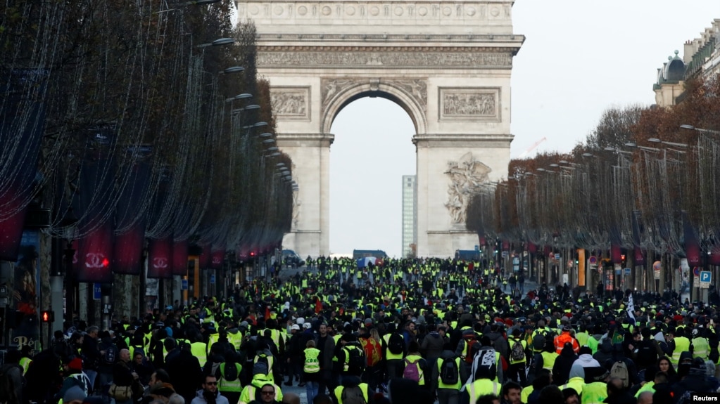 Protesters wearing yellow vests walk on the Champs-Elysees Avenue with the Arc de Triomphe in the background during a national day of protest by the "yellow vests" movement in Paris, Dec. 8, 2018.
